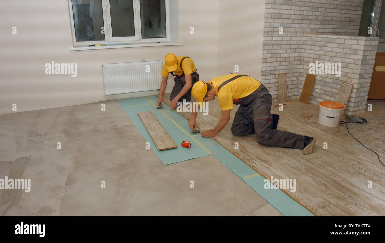 Lavoratori la posa di pavimenti in laminato. Costruttori professionali di lavorare sul pavimento nella nuova casa. Home concetto di rinnovamento. Foto Stock