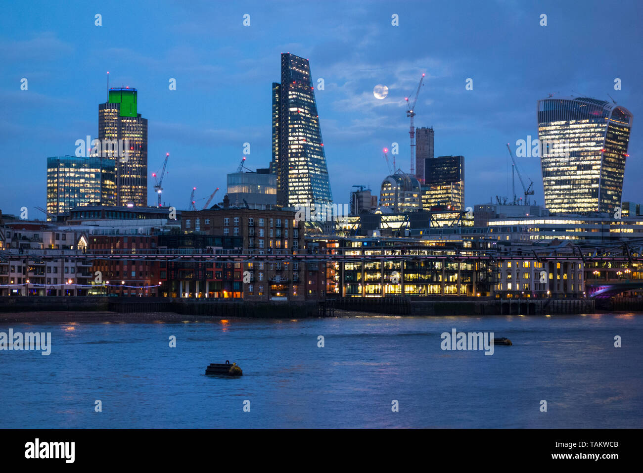 11 gennaio 2017, Londra, Regno Unito. Luna piena dietro le nuvole sopra grattacieli nella città di Londra con office luci riflesse nel fiume Tamigi. Foto Stock