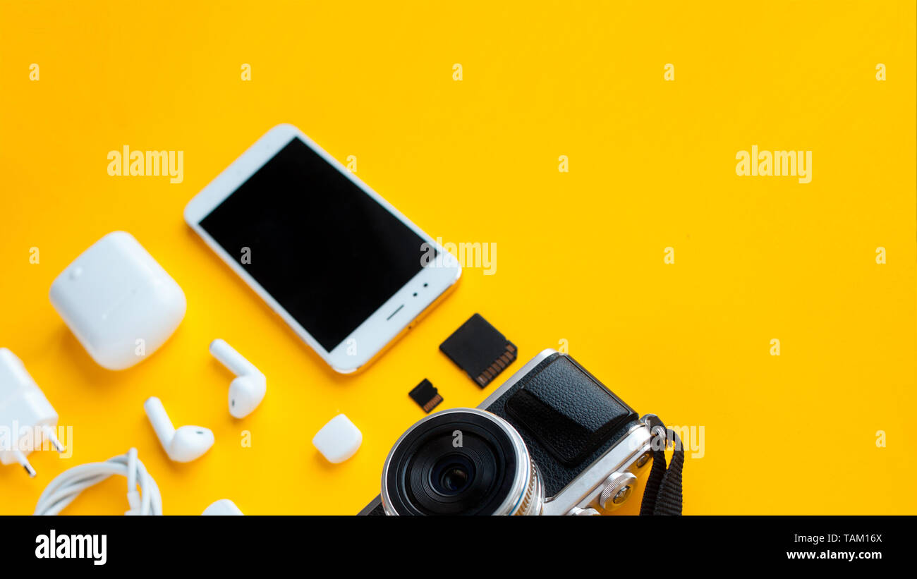 Impostare per blogger, creatore di contenuti o viaggiatore. Fotocamera Mirrorless, smartphone e gli accessori, sfondo giallo Foto Stock