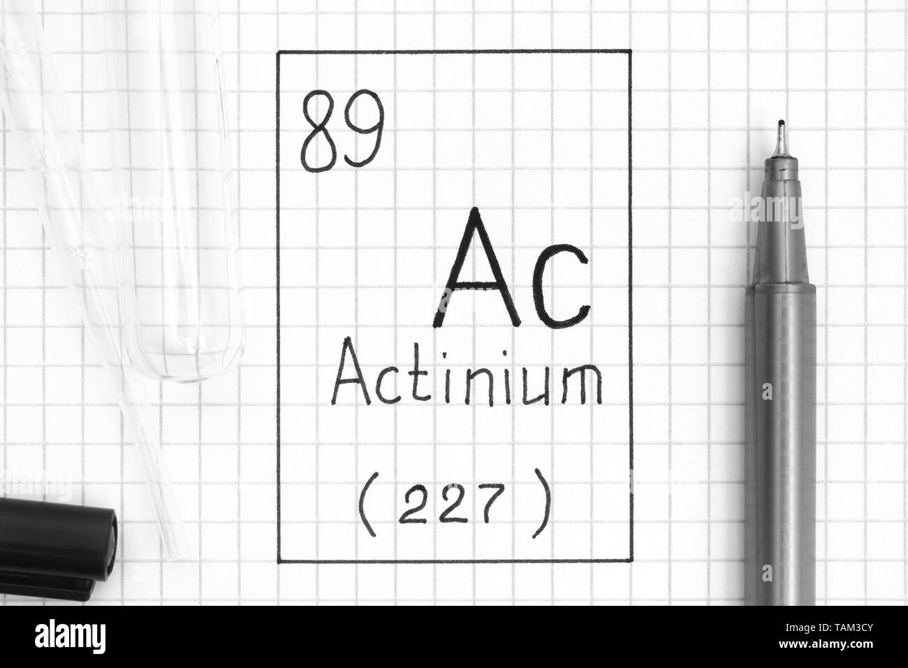 Tavola periodica degli elementi. La grafia elemento chimico Attinio Ac con la penna nera, tubo di prova e la pipetta. Close-up. Foto Stock