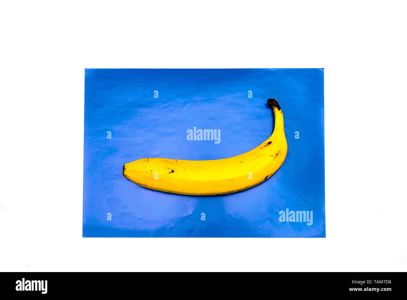 Banana, succhi di frutta con paglia su uno sfondo blu. La paglia si trova su uno sfondo blu a forma di vela e onde. La minima nozione di frutta dando il mio Foto Stock