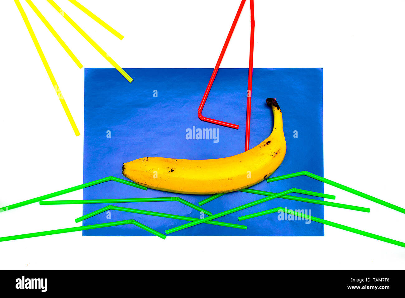 Banana, succhi di frutta con paglia su uno sfondo blu. La paglia si trova su uno sfondo blu a forma di vela e onde. La minima nozione di frutta dando il mio Foto Stock