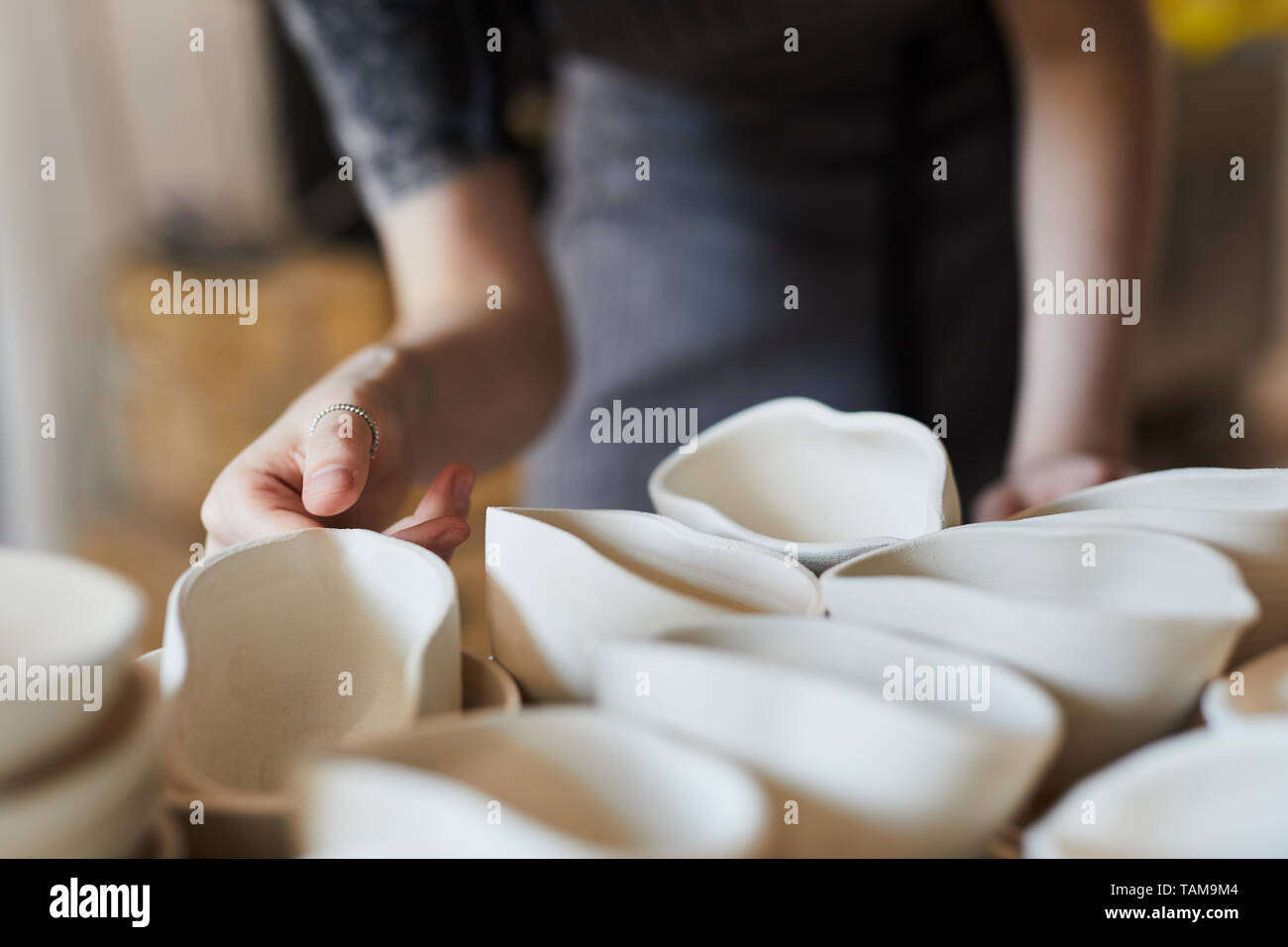 Close-up di un irriconoscibile donna con anello permanente al ripiano con prodotti ceramici e scegliendo la salsa di ceramica barca a forma di guscio di bocca Foto Stock