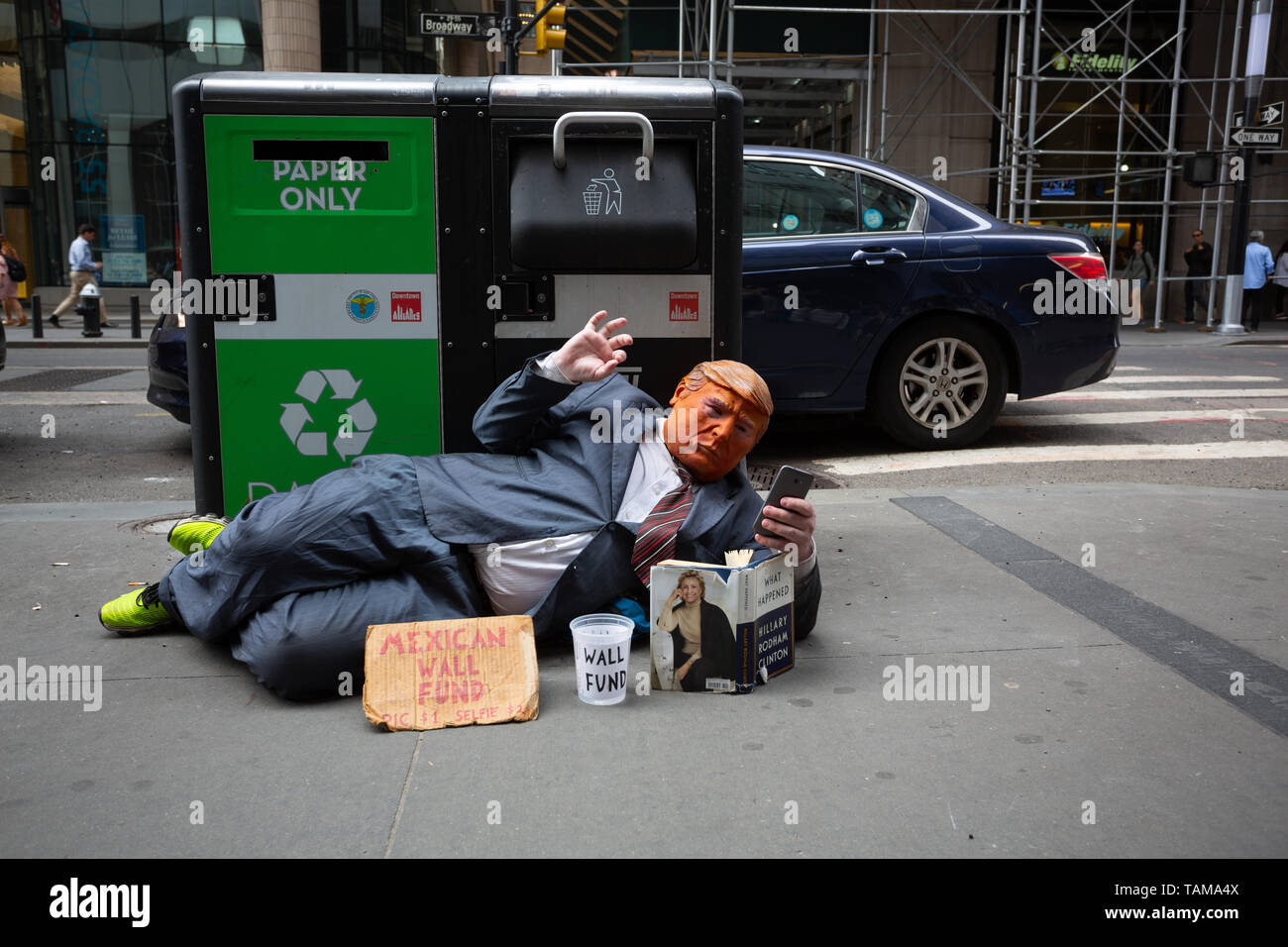 L'uomo posa sul marciapiede davanti a un garage può indossare una tuta e maschera e la rappresentazione di Donald Trump in Manhattan Financial District - New York City Foto Stock