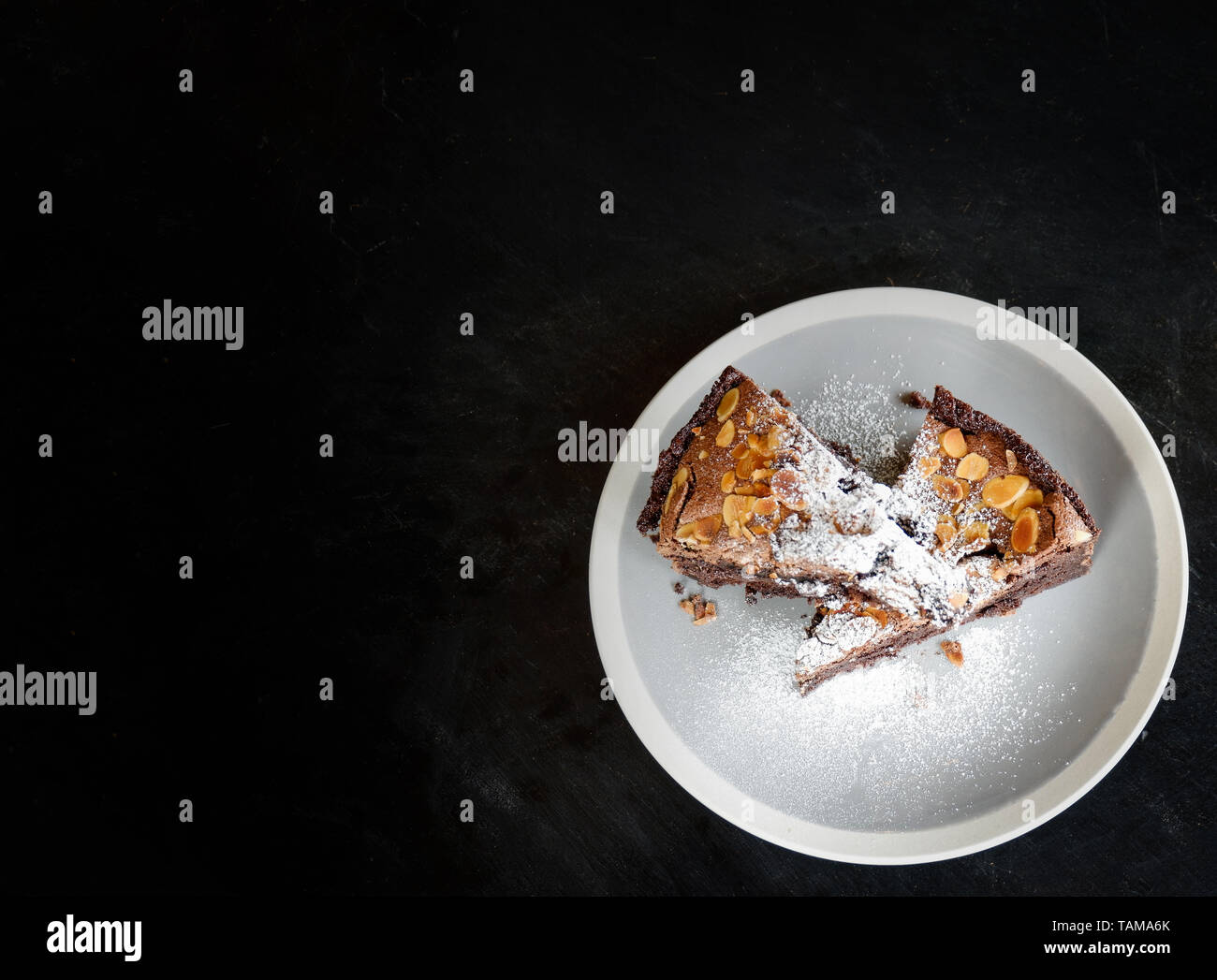 brownies cake on the table / piece of chocolate cake cocoa with nut and icing sugar on top view brownies slice on white plate the wooden dark backgrou Foto Stock