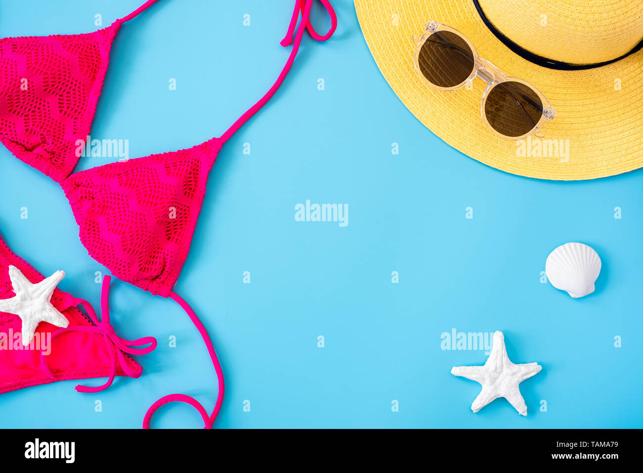 Estate banner blu con cappello giallo ,bikini rosa,occhiali da sole e la conchiglia su sfondo blu vista dall'alto. Foto Stock