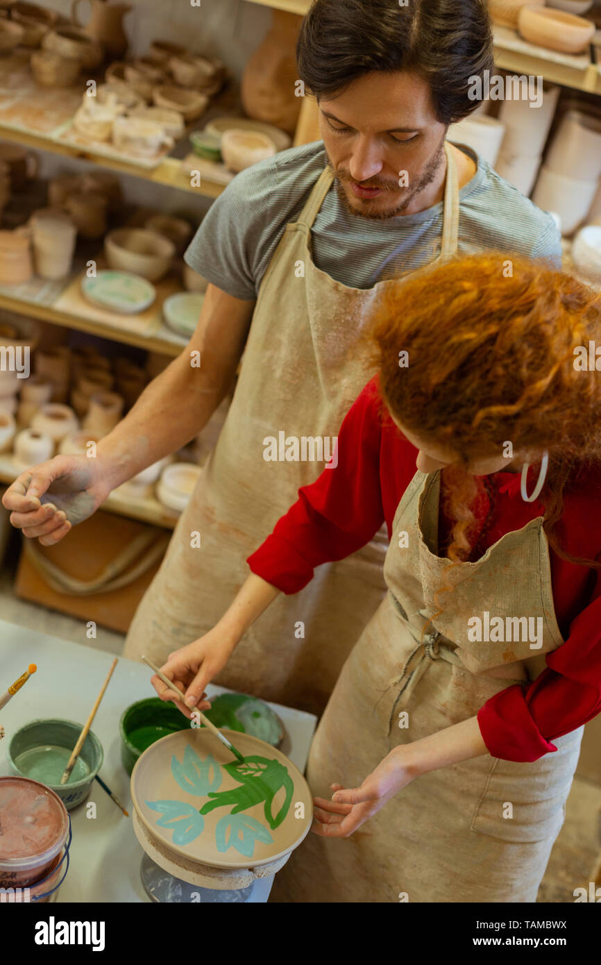 Fiori verdi. Focalizzato coppia giovane essendo concentrata su opere d'arte mentre soggiornate nel laboratorio di ceramica tutto il giorno Foto Stock