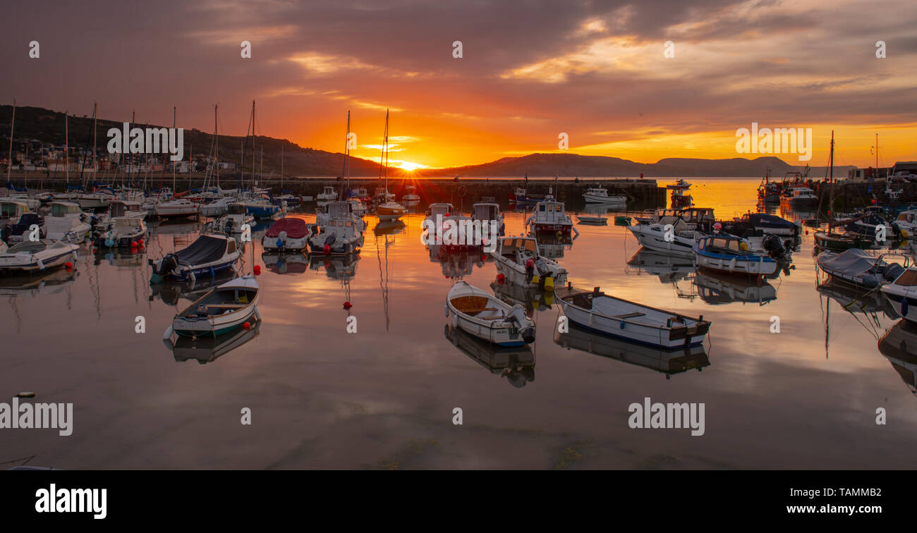 Lyme Regis, Dorset, Regno Unito. 27 maggio 2019. Regno Unito Meteo: Moody sunrise colori sono riflesse in acqua calma a Cobb a Lyme Regis sulla fine Maggio Bank Holiday.. Credito: Celia McMahon/Alamy Live News. Foto Stock