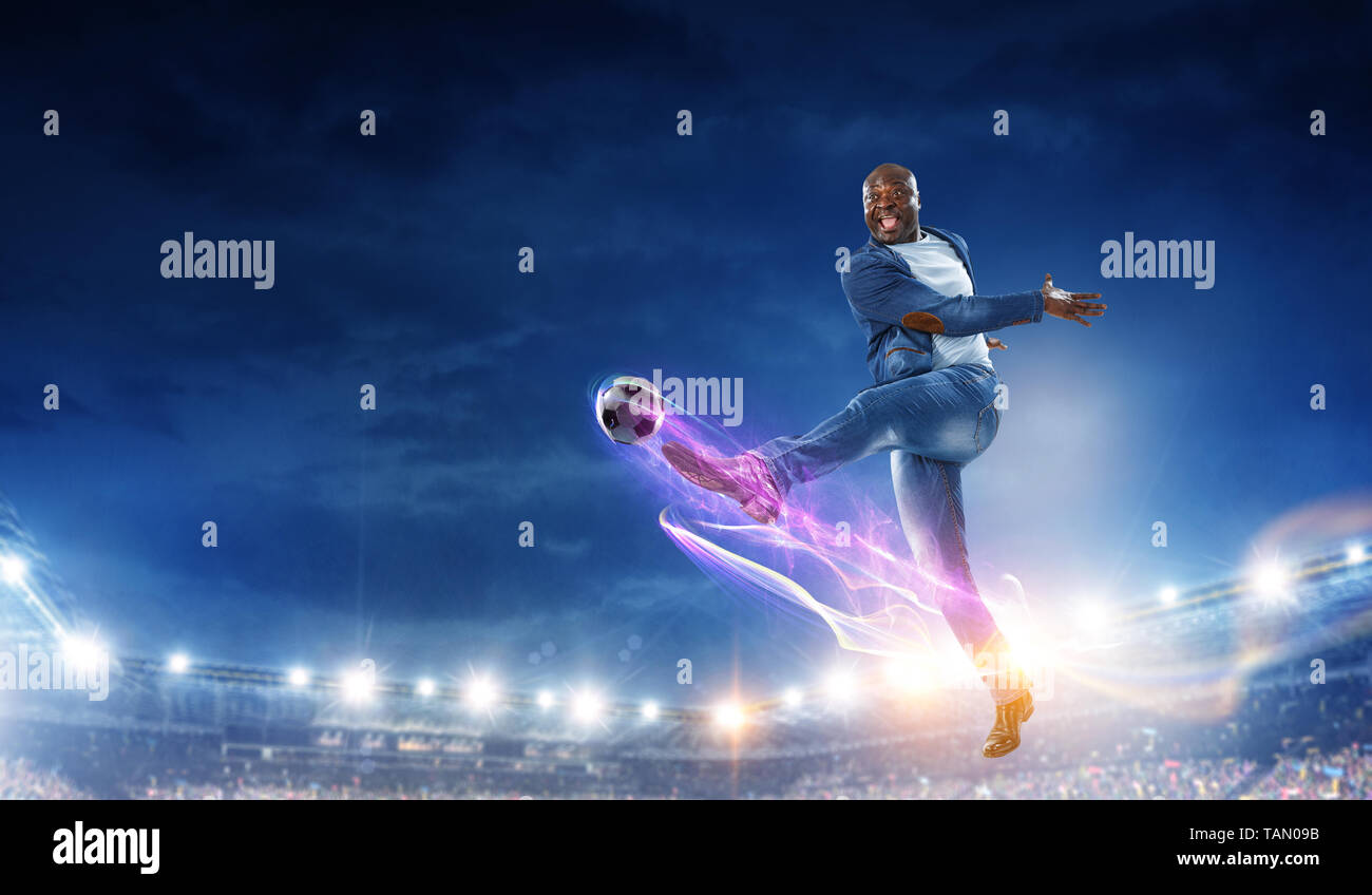 Uomo in nero abiti casual gioca a calcio su un Stadium. I supporti misti Foto Stock