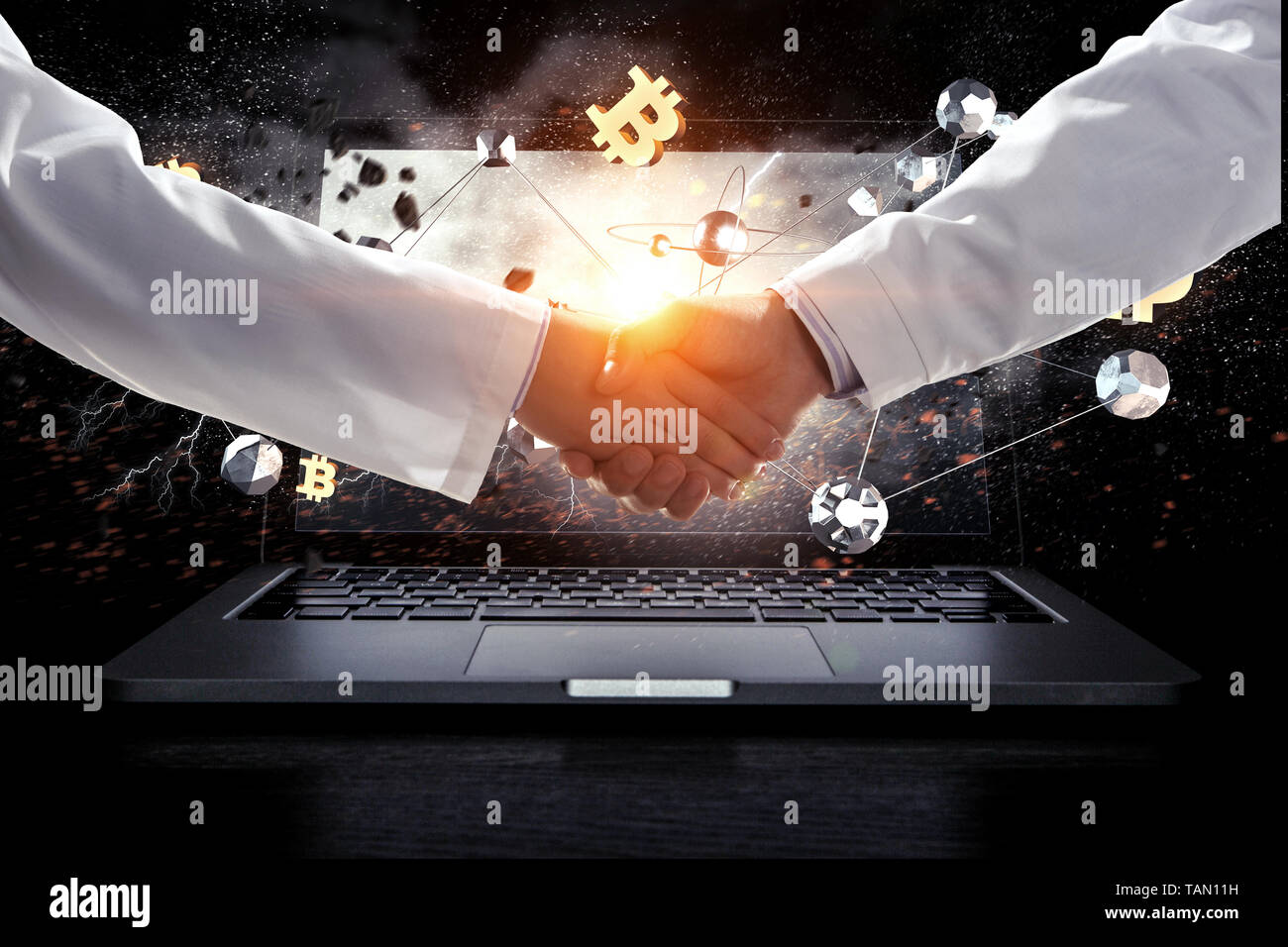 Handshake aziendale da parte di un uomo e di una donna, laptop e bitcoin simboli. I supporti misti Foto Stock