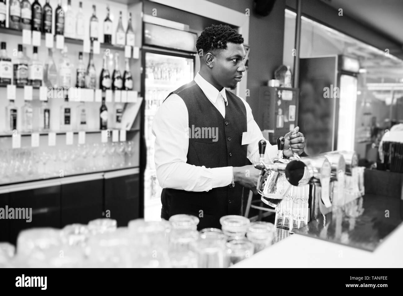 African American barista presso il bar versando da toccare birra fresca nel vetro nel pub. Foto Stock