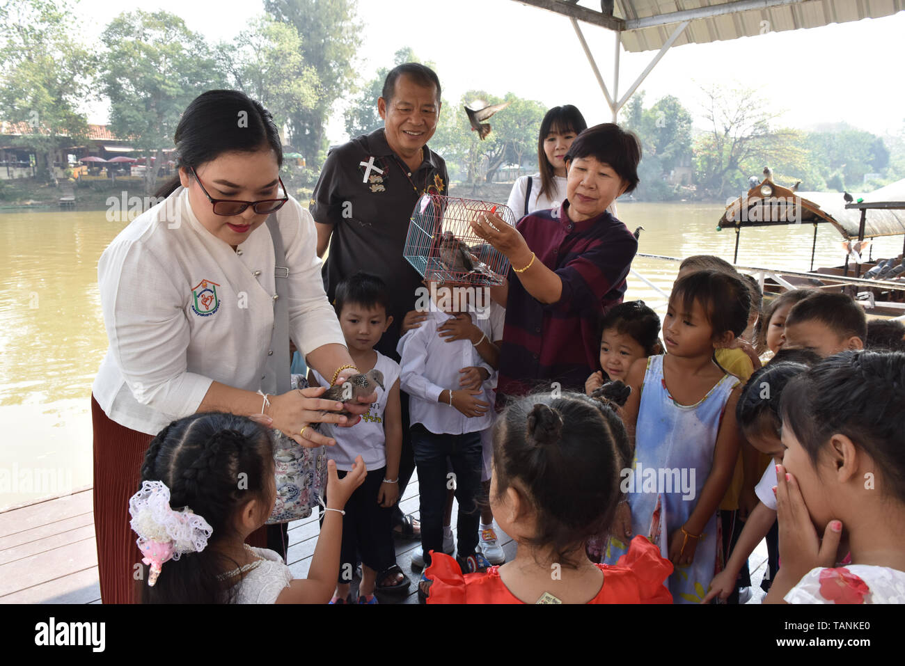 Bambini tailandesi e i loro educatori uccelli di rilascio accanto al fiume Ping Chiang Mai .nella religione buddista, alcune persone credono che il rilascio di animali torna in natura possono aiutare un individuo a maturare il merito. Foto Stock