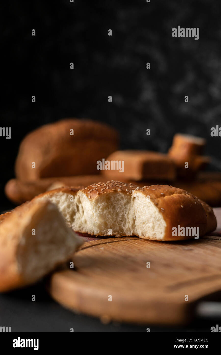 Pane appena sfornato soffice dolce diviso bun con semi di sesamo su di esso, strappato pezzo di pane Foto Stock