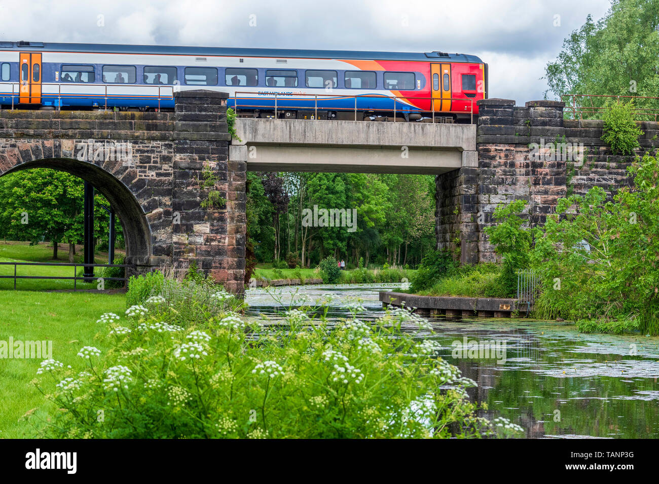 Il treno attraversa ponte sopra il Sankey canal in Sankey Valley Park. Foto Stock