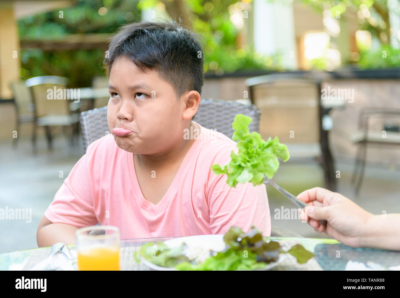 Obesi Fat Boy con espressione di disgusto contro le verdure in insalata, rifiutando il concetto di cibo Foto Stock