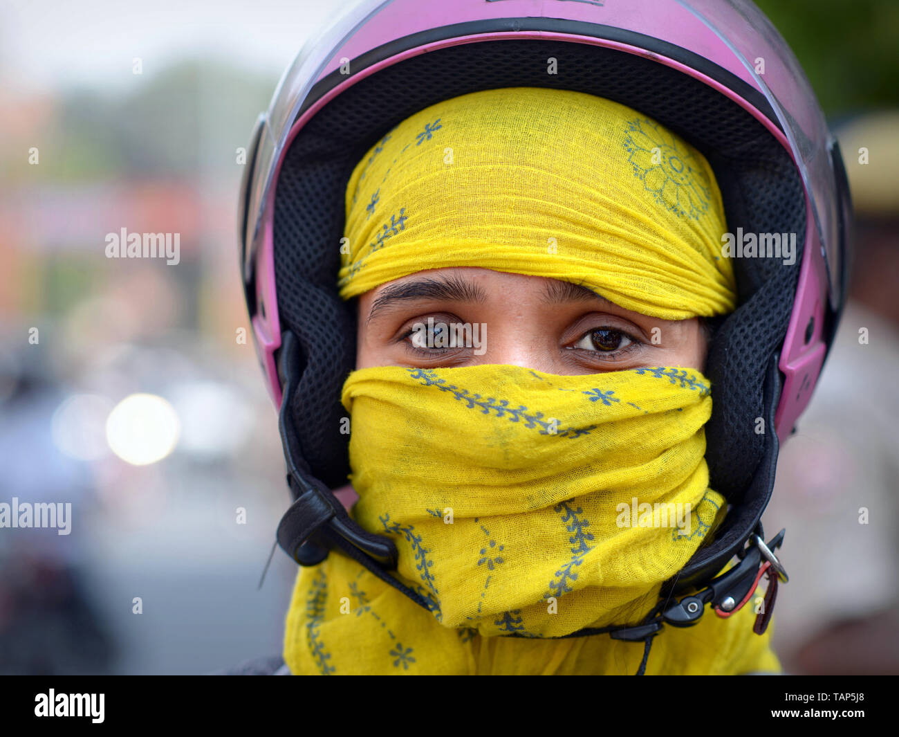 Rajasthani indiano scooter ragazza con un viola casco si copre la faccia con un giallo secolare velo di polvere. Foto Stock