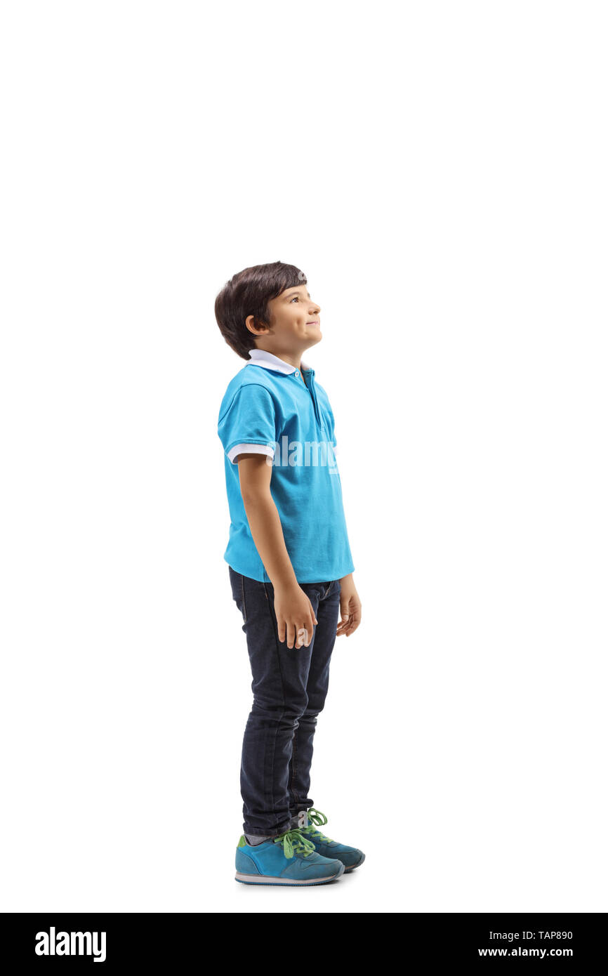 Lunghezza piena ripresa di profilo di un ragazzo sorridente in piedi e guardando verso l'alto isolato su sfondo bianco Foto Stock