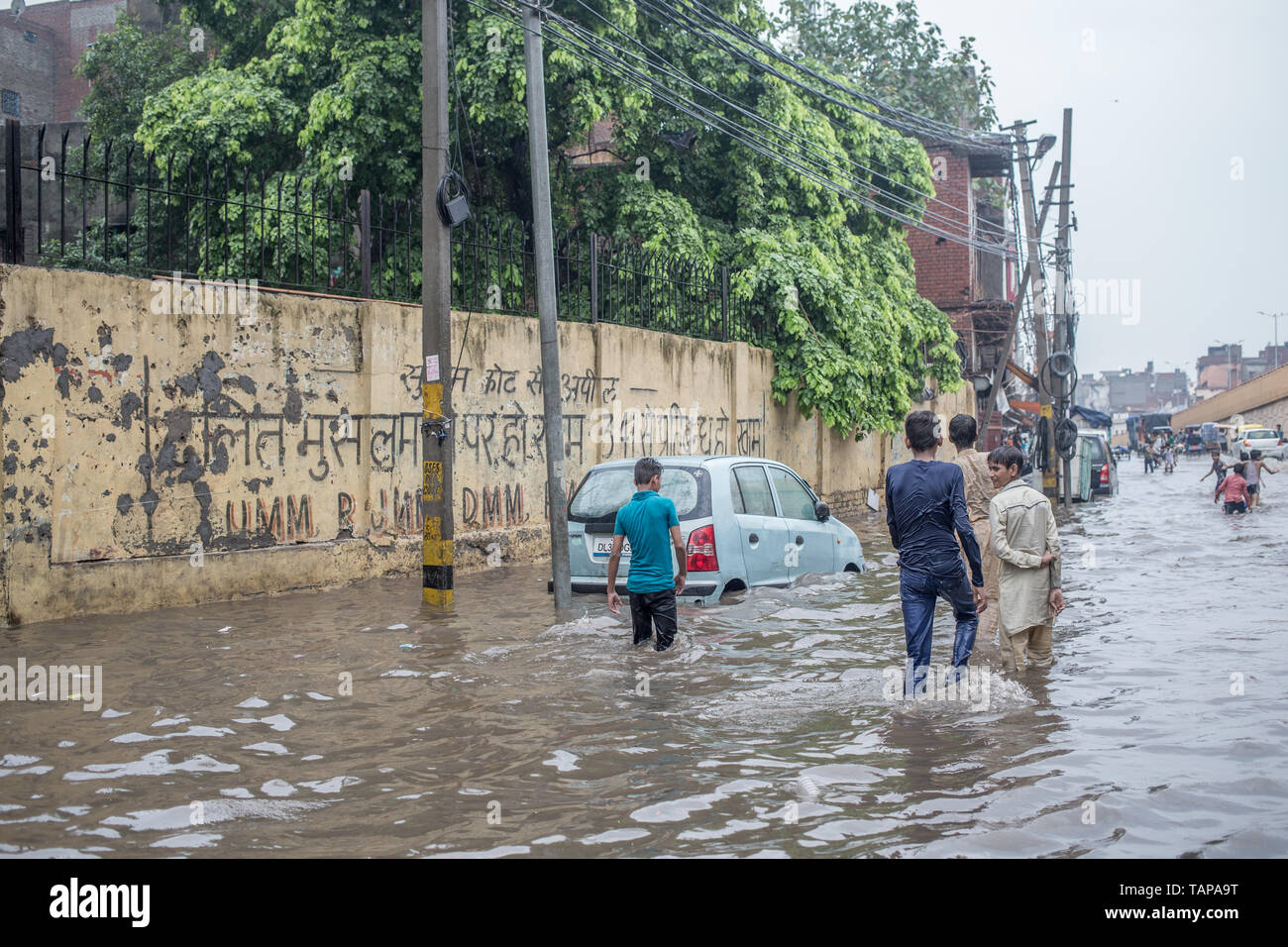 La Gioventù a camminare in una strada allagata dopo le piogge in New Delhi, India. Foto Stock