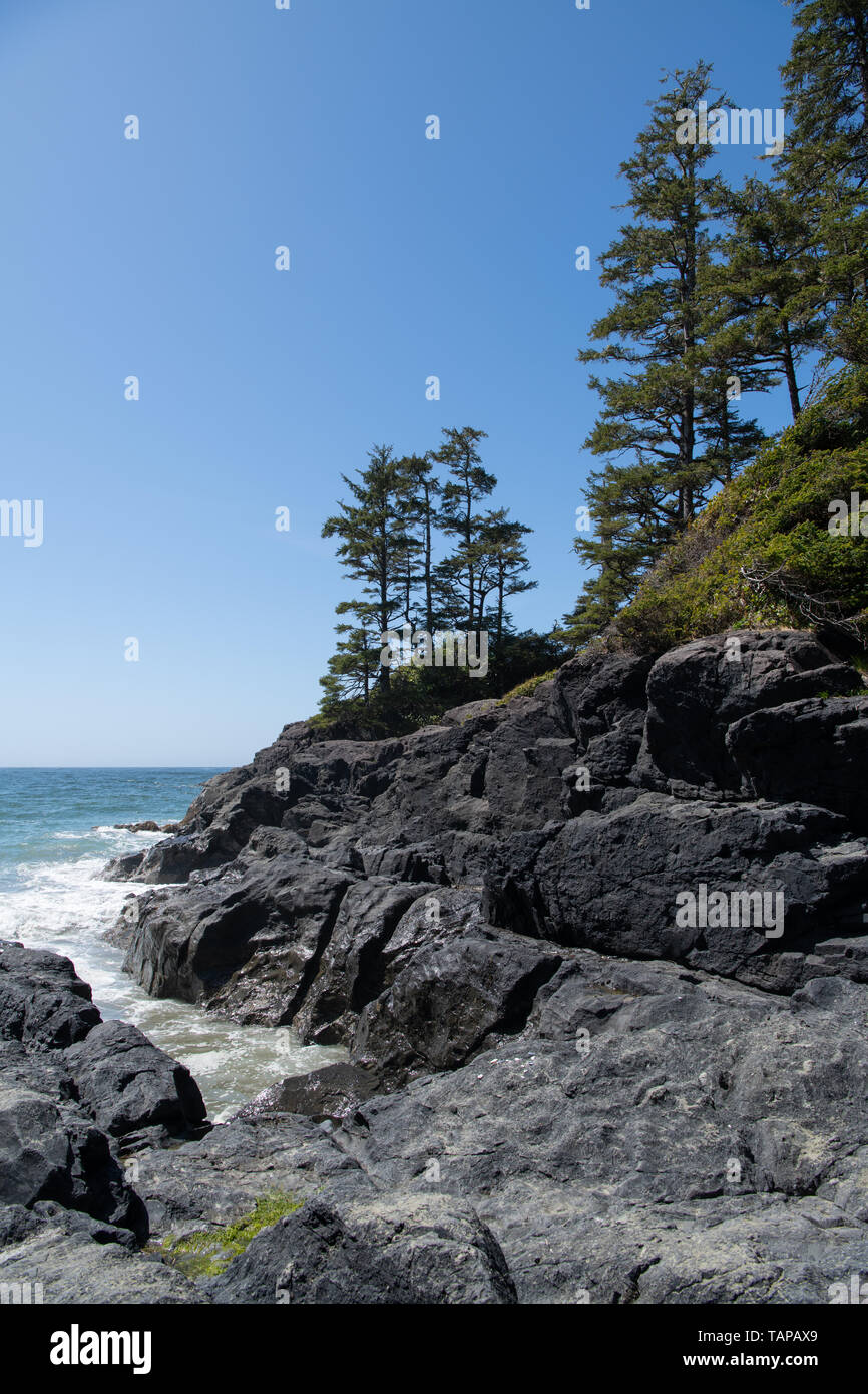 Cielo blu e mare calmo visto con insenatura rocciosa in primo piano, Tofino Vancouver Island, British Columbia, Canada Foto Stock