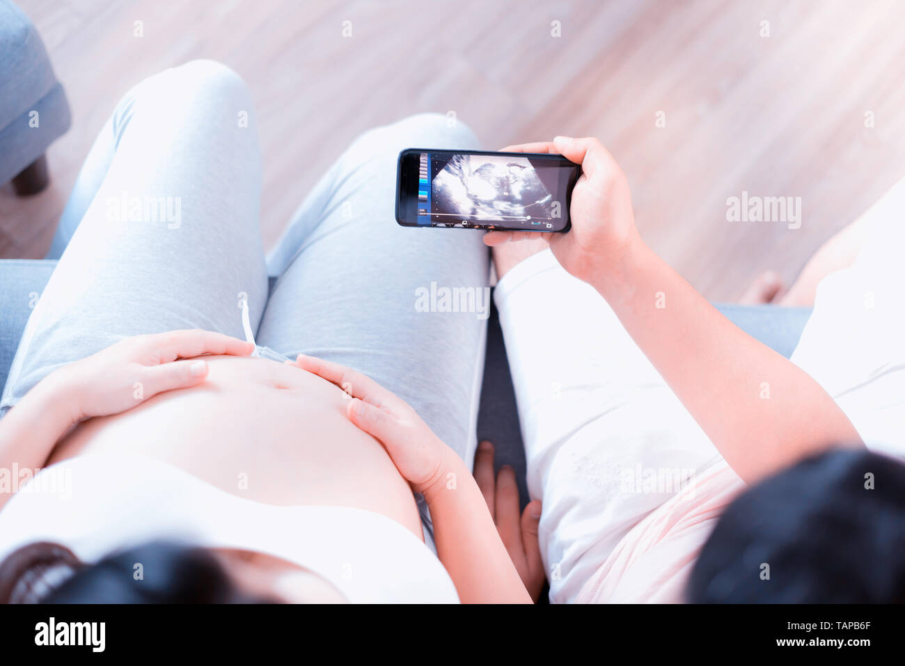 Asian donna incinta con grande pancia. Festa della mamma e la giornata internazionale delle donne. Mom neonato cercando xray sul mobile. Foto Stock