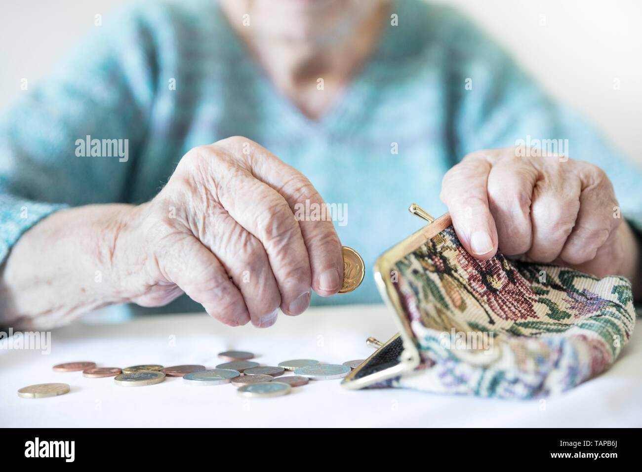 Primo piano dettagliato foto di un irriconoscibile anziani womans mani restanti di conteggio delle monete in euro dalla pensione nel suo portafoglio dopo il pagamento di fatture. Foto Stock