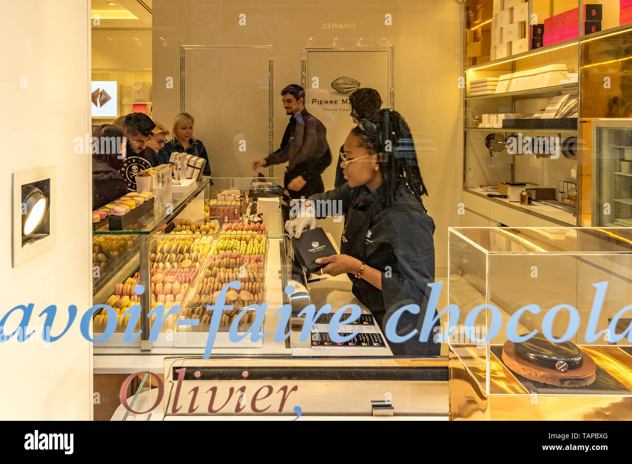 Persone che acquistano macarons in Pierre Marcolini un belga di lusso negozio di cioccolato Les Galeries Royales Saint-Hubert , vetrato shopping arcade a Bruxelles . Foto Stock