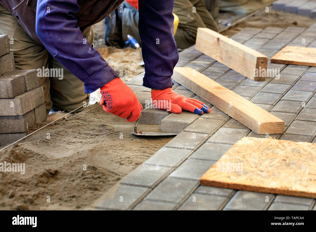 Il lavoratore livelli la piattaforma per la posa di pavimentazioni con l aiuto di una spatola di legno e barre, allineandola al livello del filo teso. Foto Stock