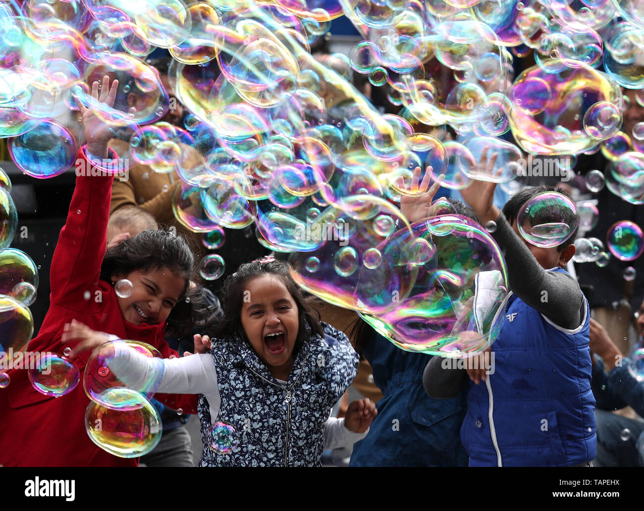 I bambini cercano di prendere le bolle da un esecutore di strada su lunedì festivo lungo il Royal Mile di Edimburgo. Foto Stock