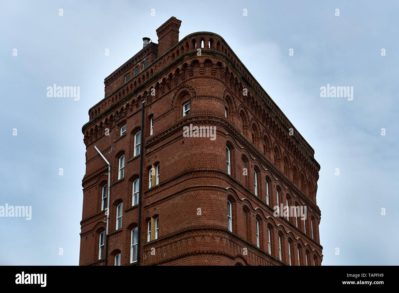 Un edificio in mattoni rossi del XX secolo sorge isolato contro un cielo pallido a Leeds, nello Yorkshire. REGNO UNITO Foto Stock