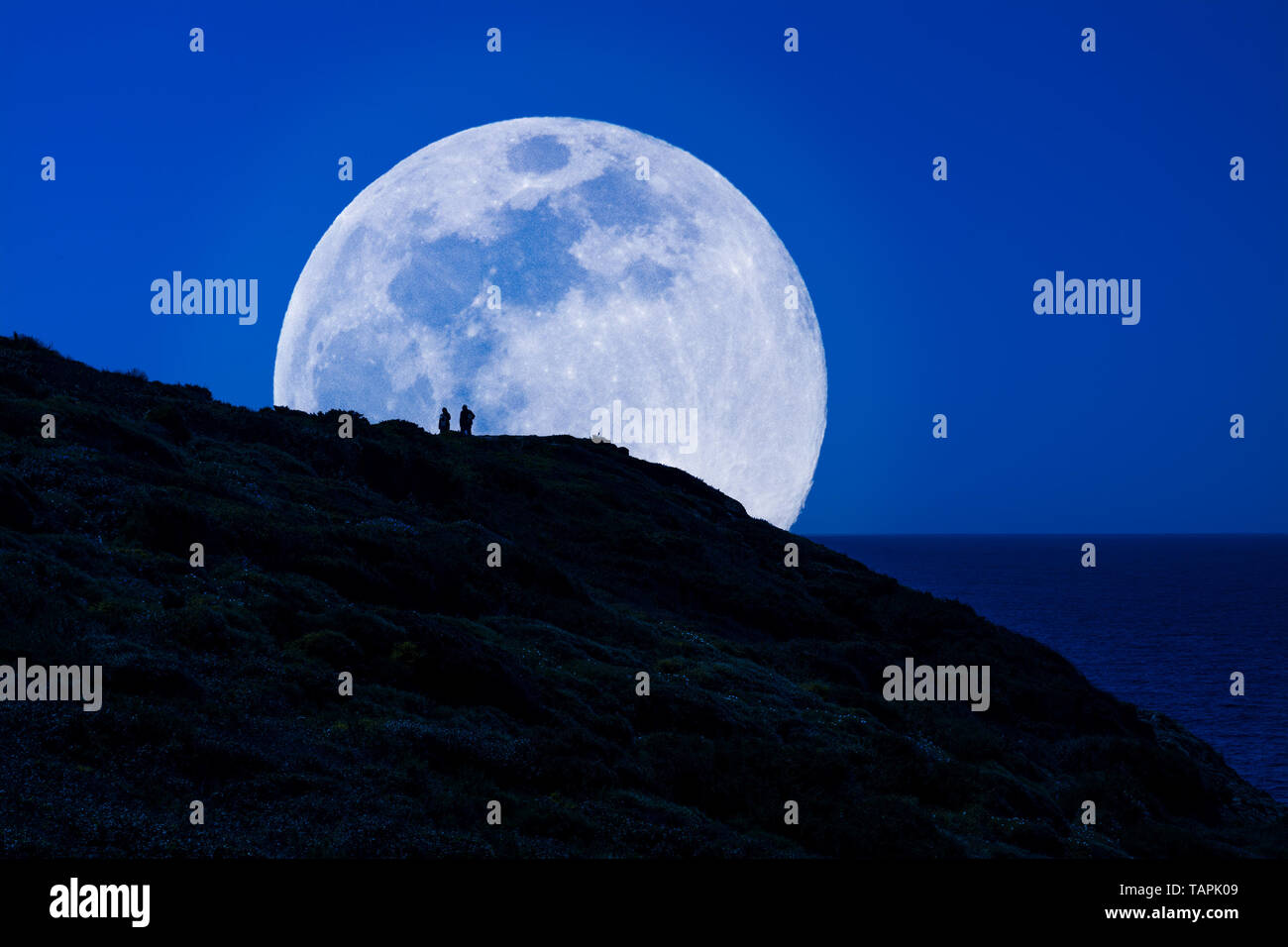 Silhouette di uomini sotto il super luna Foto Stock