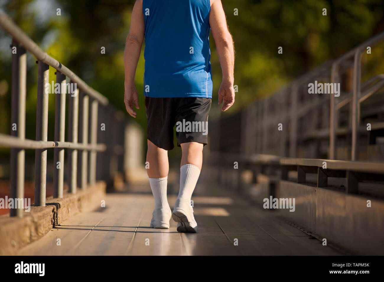 Senior uomo a camminare attraverso gradinate in sneakers. Foto Stock