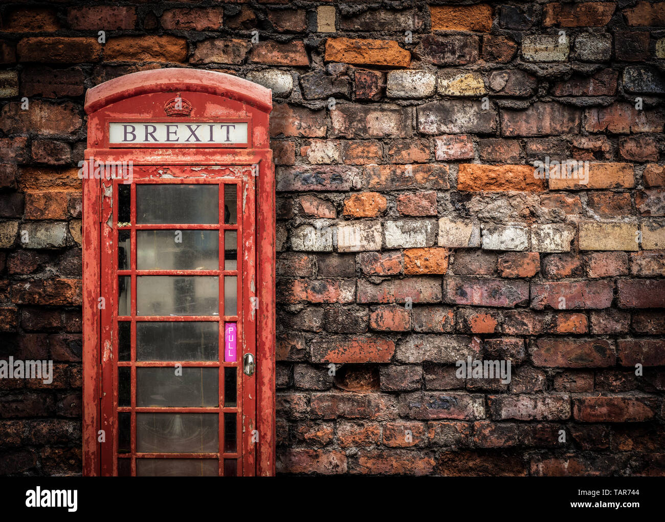 Immagine che rappresenta Brexit rotto la Gran Bretagna di un peeling vecchio telefono rosso scatola contro un Grungy rosso parete in mattoni con spazio di copia Foto Stock