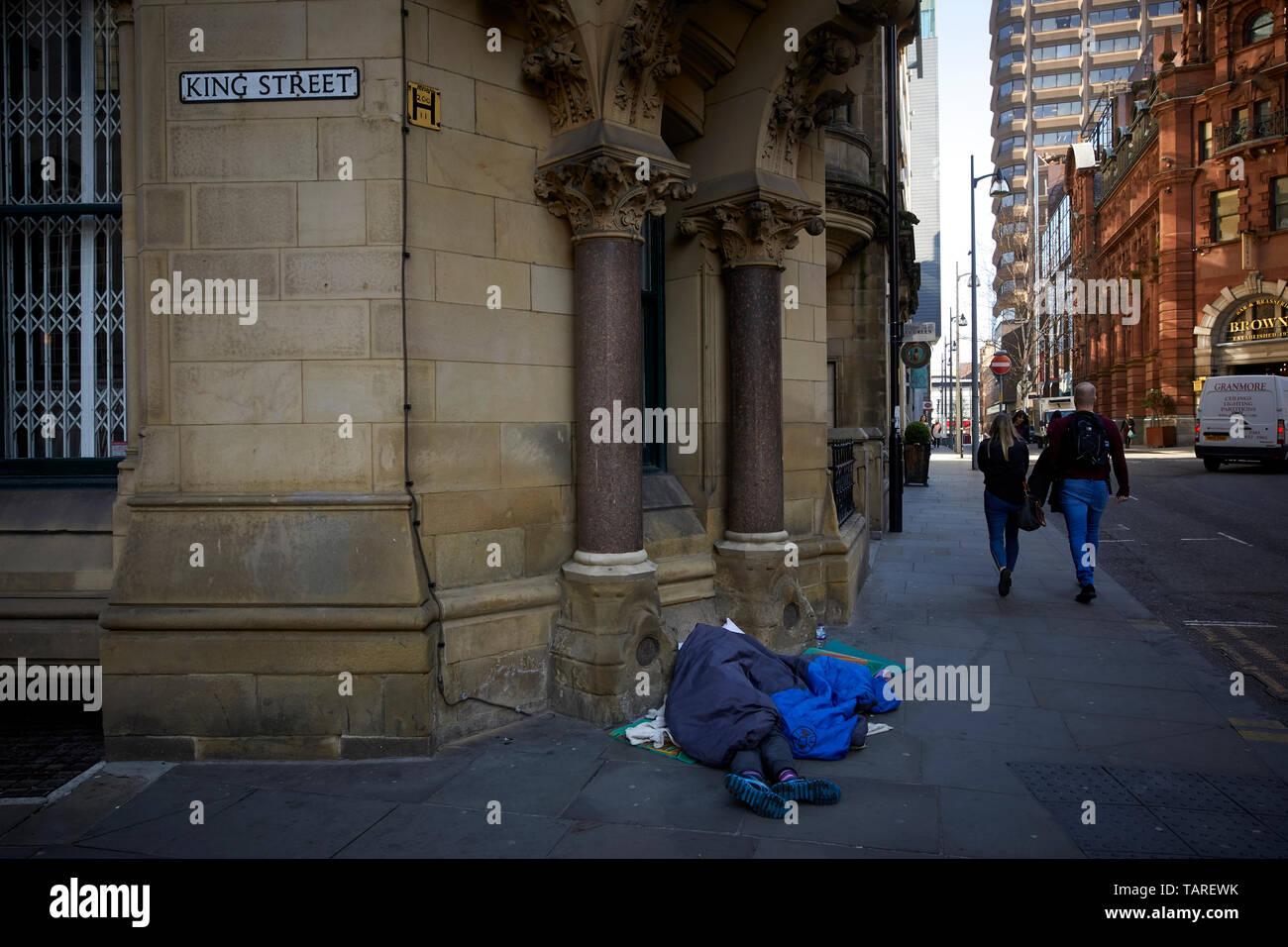 In contrasto senzatetto sonno agitato Manchester city center King Street, esclusiva destinazione per lo shopping Foto Stock