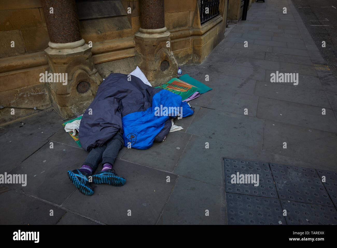 In contrasto senzatetto sonno agitato Manchester city center King Street, esclusiva destinazione per lo shopping Foto Stock