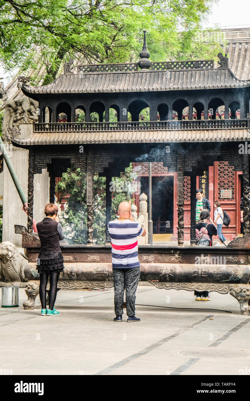 Il cinese adoratori di pregare nella parte anteriore del bruciatore di incenso in abbazia delle nuvole bianche, Pechino, Cina Foto Stock
