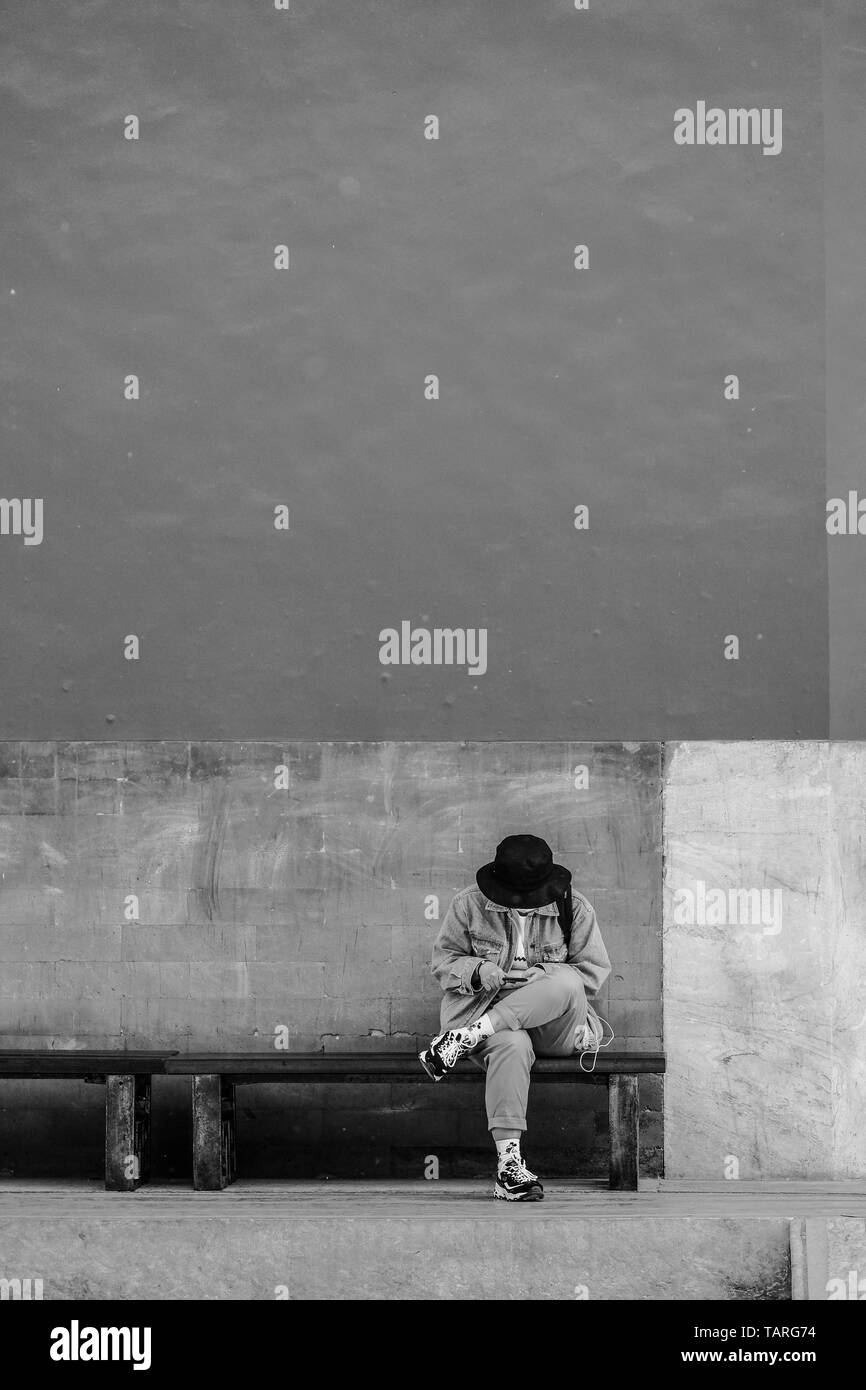 Una donna che gioca il suo smartphone di fronte alto muro rosso della Città Proibita di Pechino, Cina Foto Stock