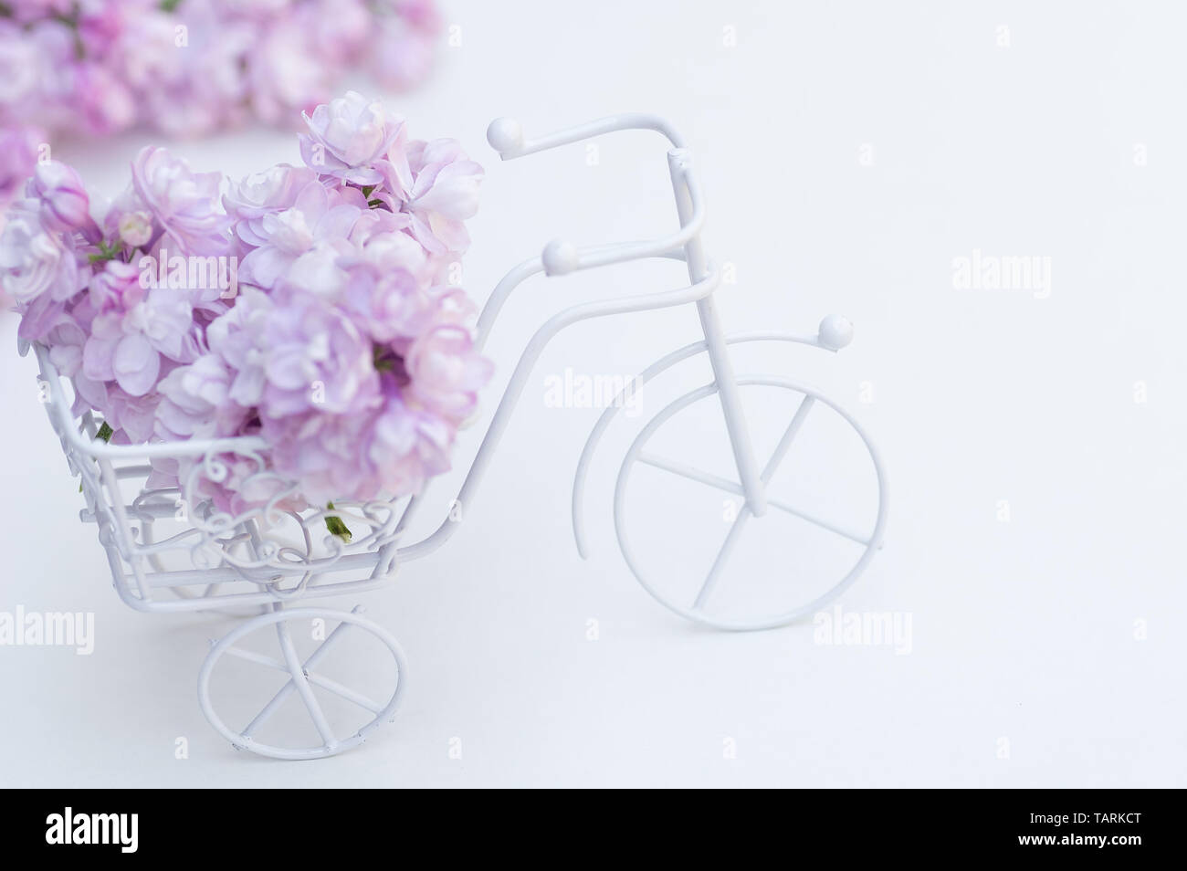 Giocattolo Vintage bike bianco. Bouquet di lilla, decorazione per le vacanze. Colori pastello. Foto Stock