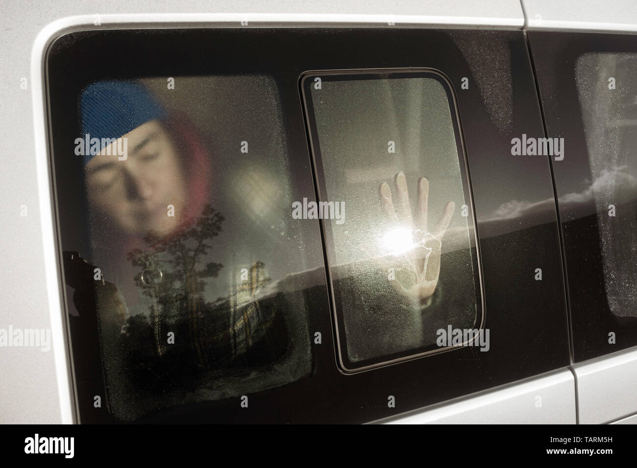 Donna che Dorme in camper van risveglio come il sorgere del sole risplende attraverso la finestra del furgone Foto Stock