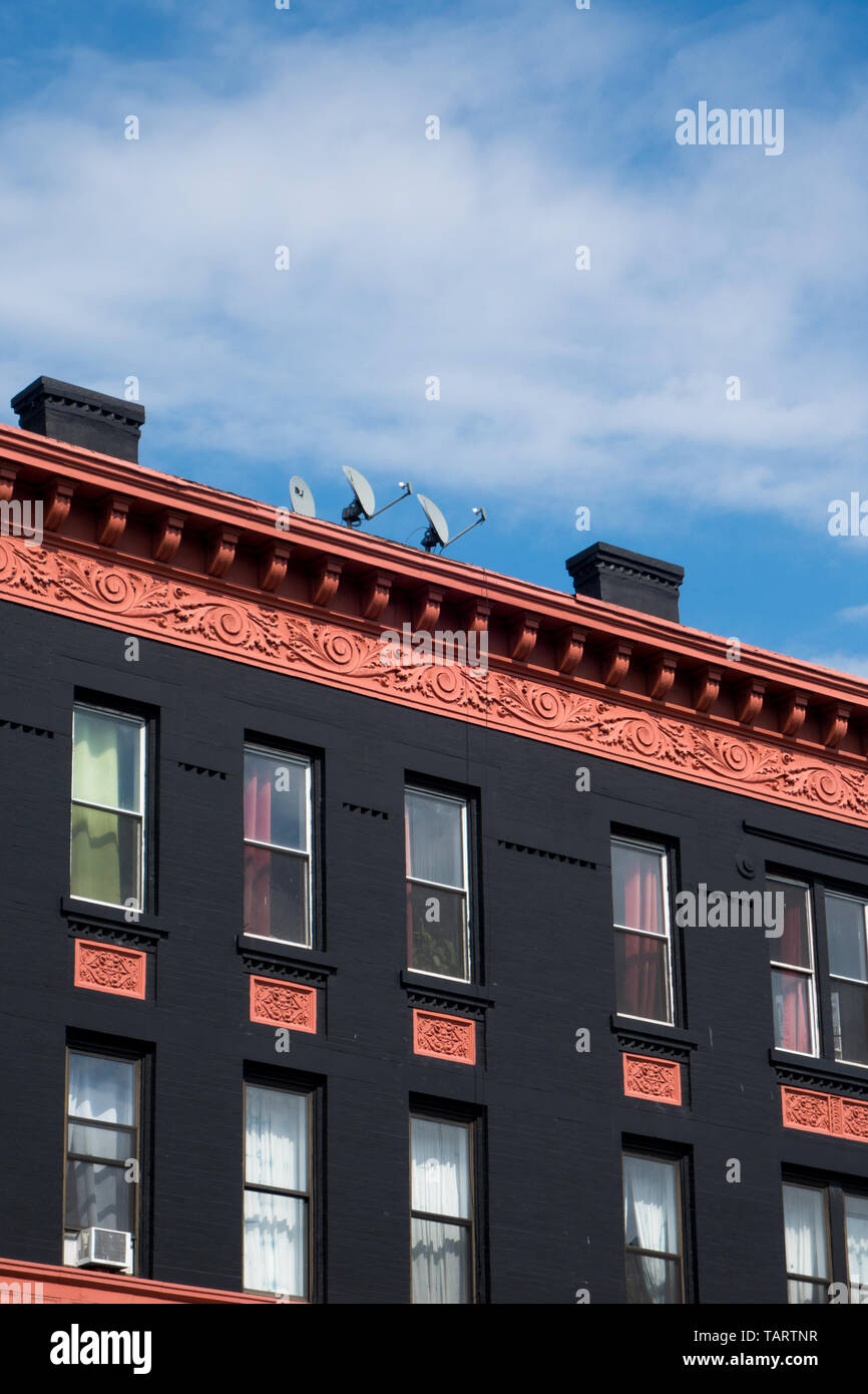 La ornata di ornamentazione architettonica sulla parte superiore di un colorato il vecchio edificio in Brooklyn, New York, USA, contro un cielo blu. Foto Stock