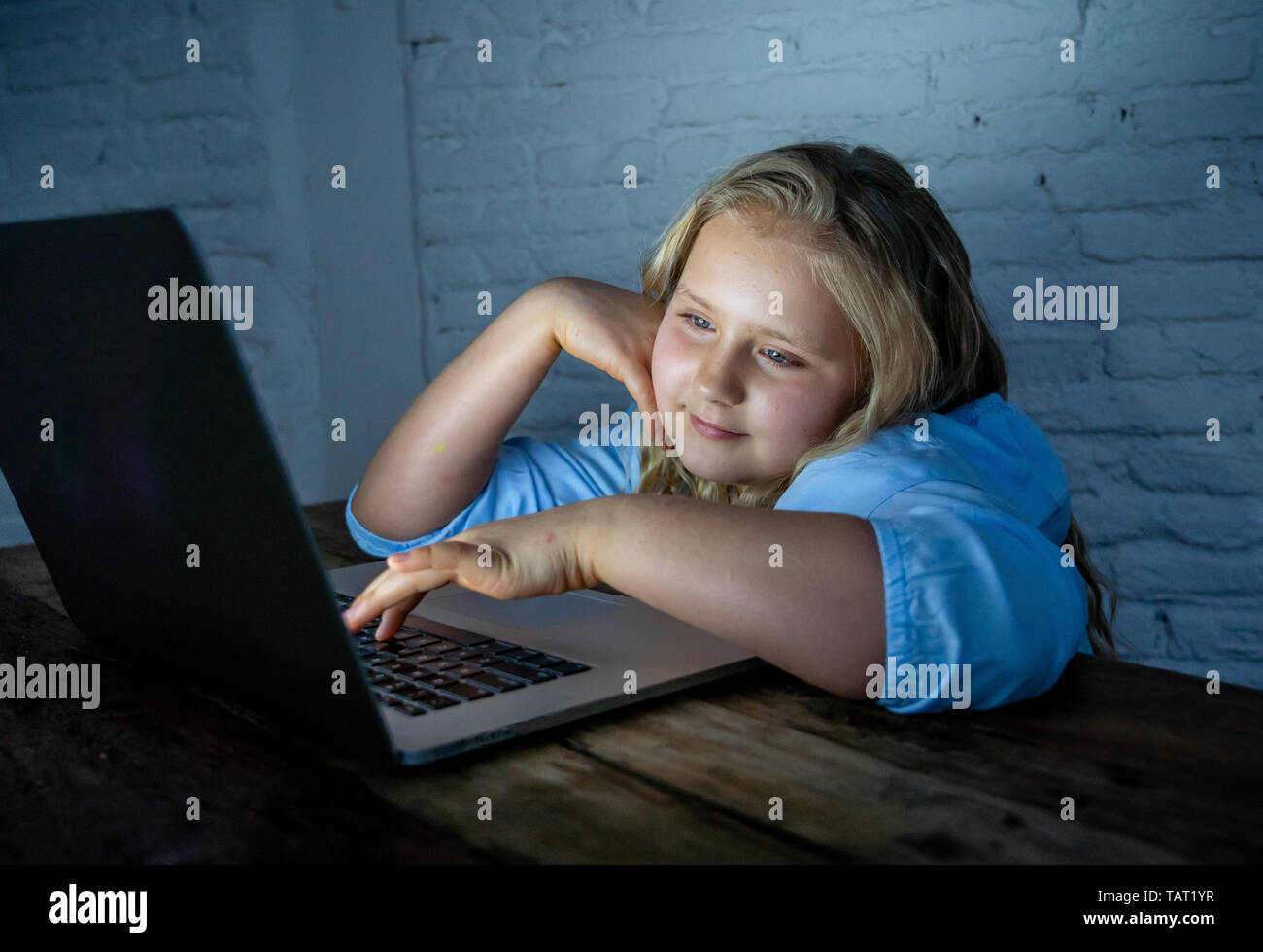 Carino schoolgirl bambino la riproduzione e la navigazione online a tarda notte. Bambino addicted ai giochi su internet e i social media non riesce a dormire agganciata sul laptop. Digita Foto Stock