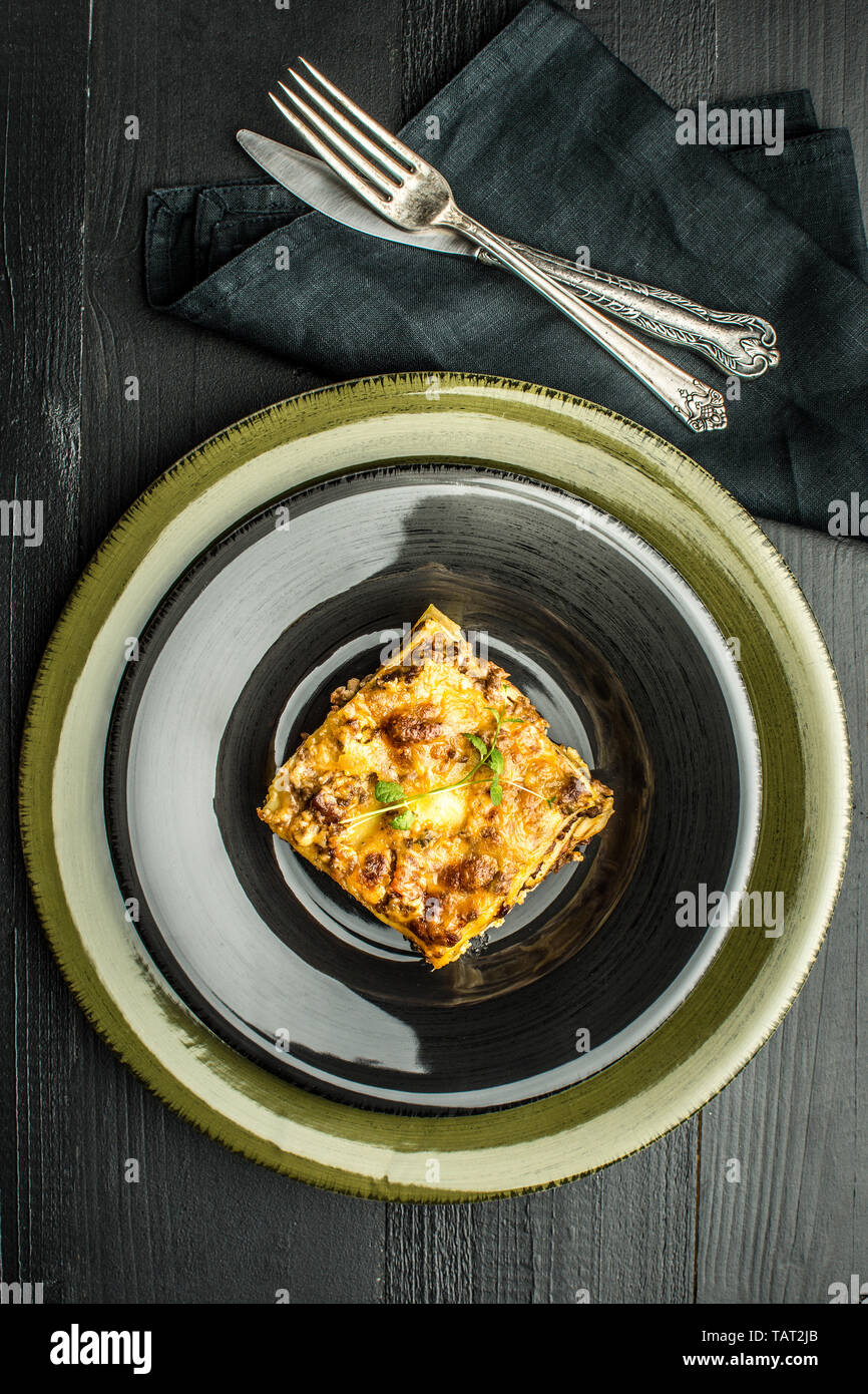 Le lasagne italiane con la carne macinata e il verde del basilico sulla piastra scuro Foto Stock