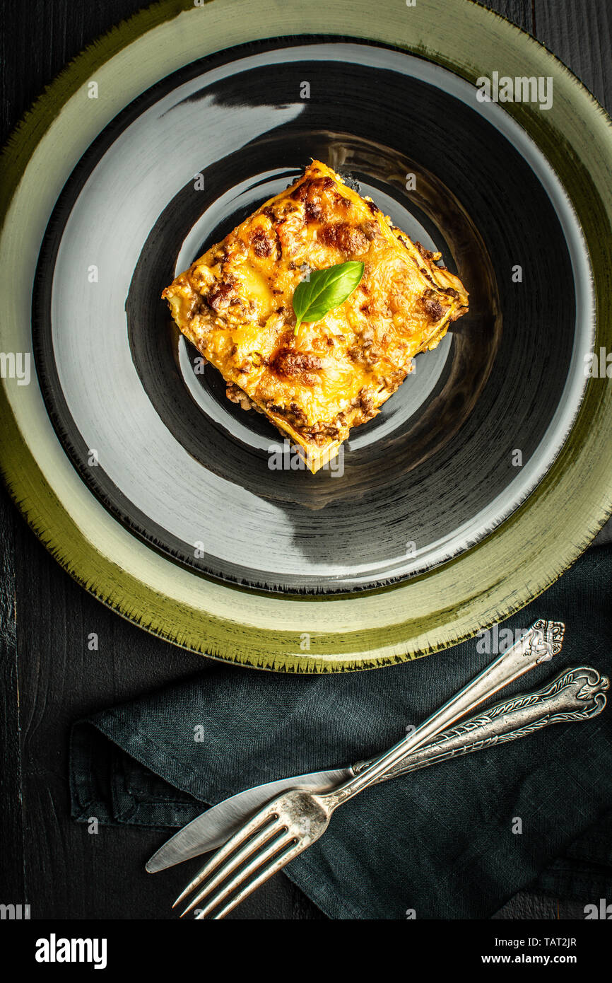 Le lasagne italiane con la carne macinata e il verde del basilico sulla piastra scuro Foto Stock