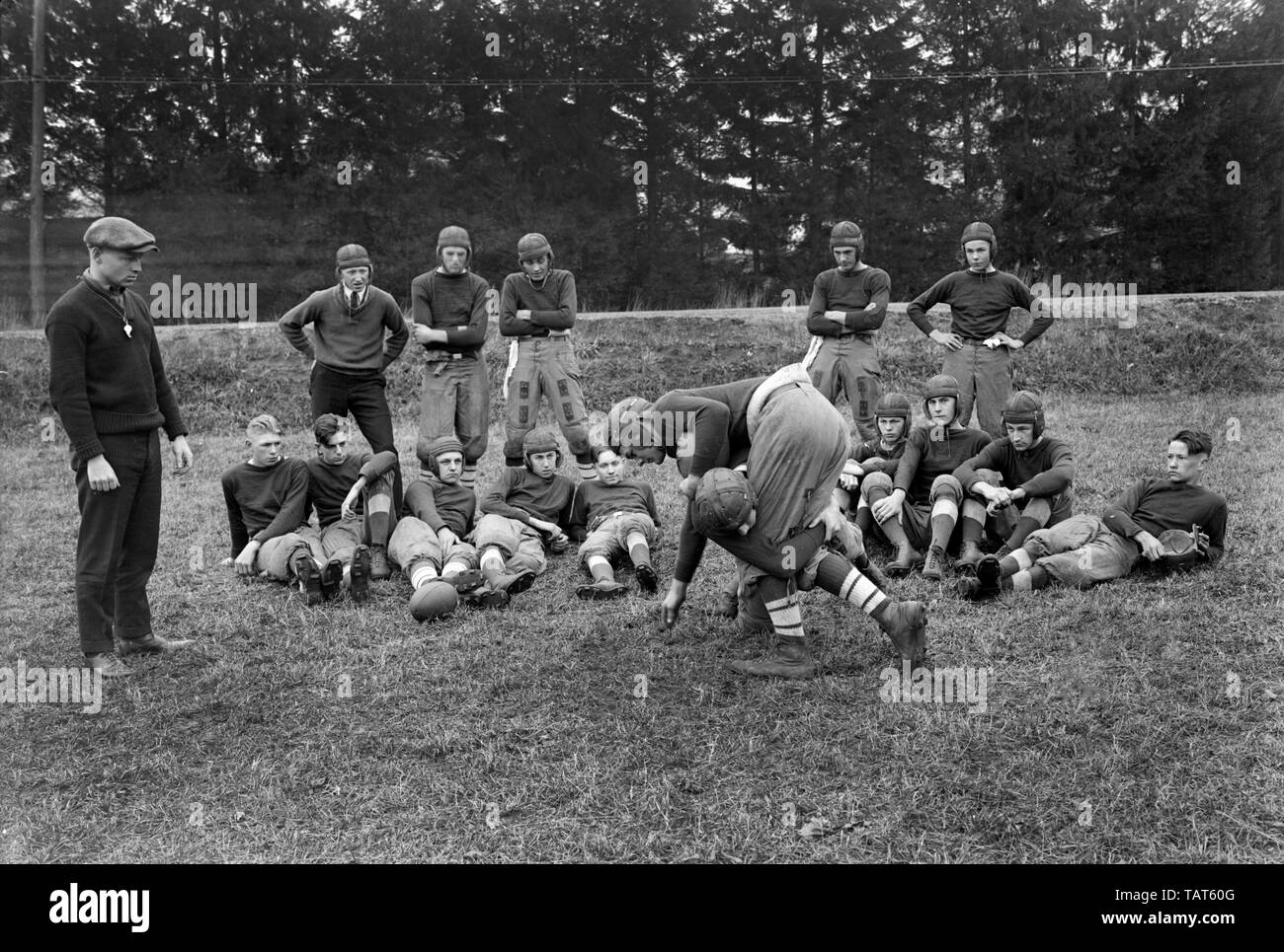 Un pullman sovrintende una pratica di gioco del calcio di affrontare seminatrice con il suo team, ca. 1925. Foto Stock