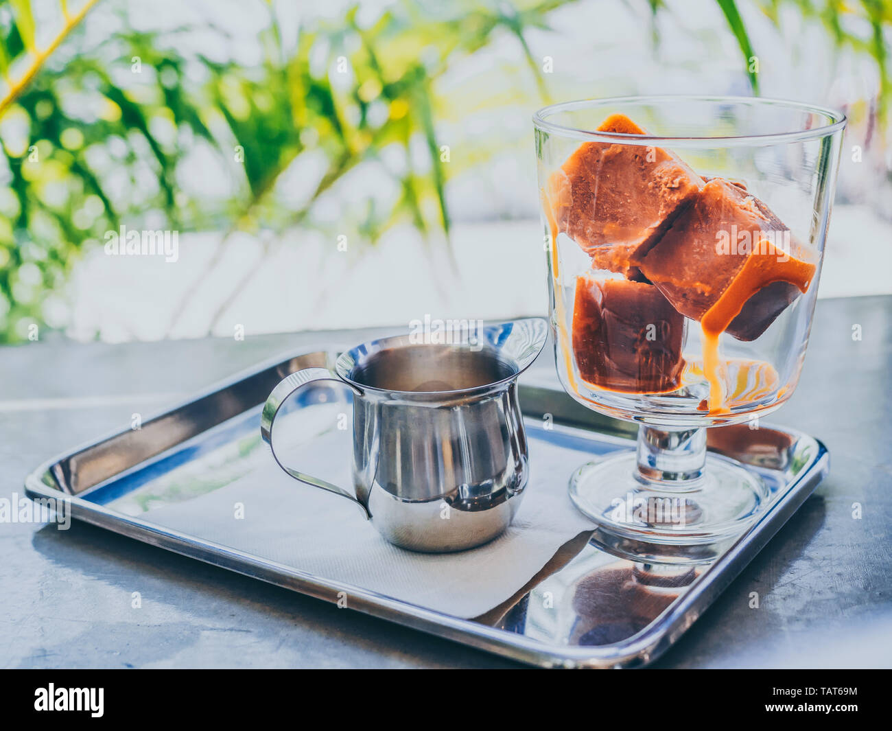 Thai tè latte di cubetti di ghiaccio nel bicchiere con il latte nel bricco  di piccole dimensioni sul vassoio in acciaio inox su cemento tabella Foto  stock - Alamy
