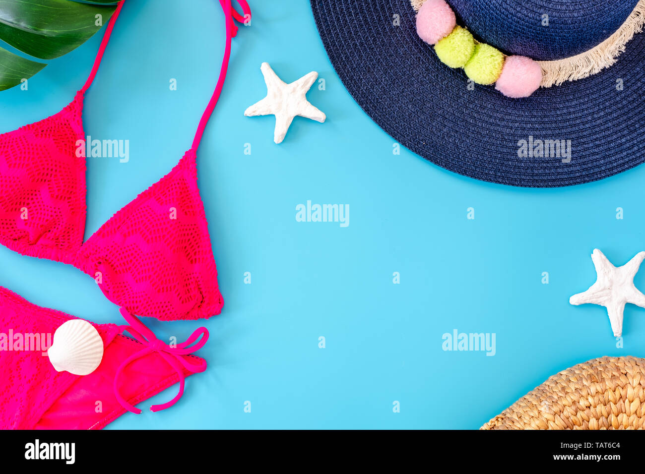 Estate banner blu con blu navy hat ,bikini rosa,occhiali da sole e la conchiglia su sfondo blu vista dall'alto. Foto Stock