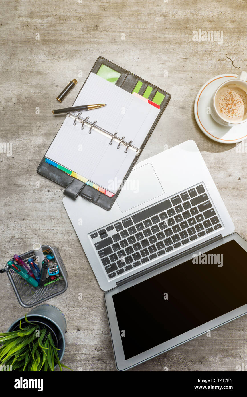 Vista superiore del banco affari con computer portatile, caffè, pianta in vaso, notebook e accessori business per l'ufficio Foto Stock