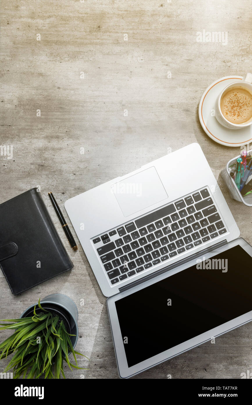 Vista superiore del banco affari con computer portatile, caffè, pianta in vaso, notebook e accessori business per l'ufficio Foto Stock