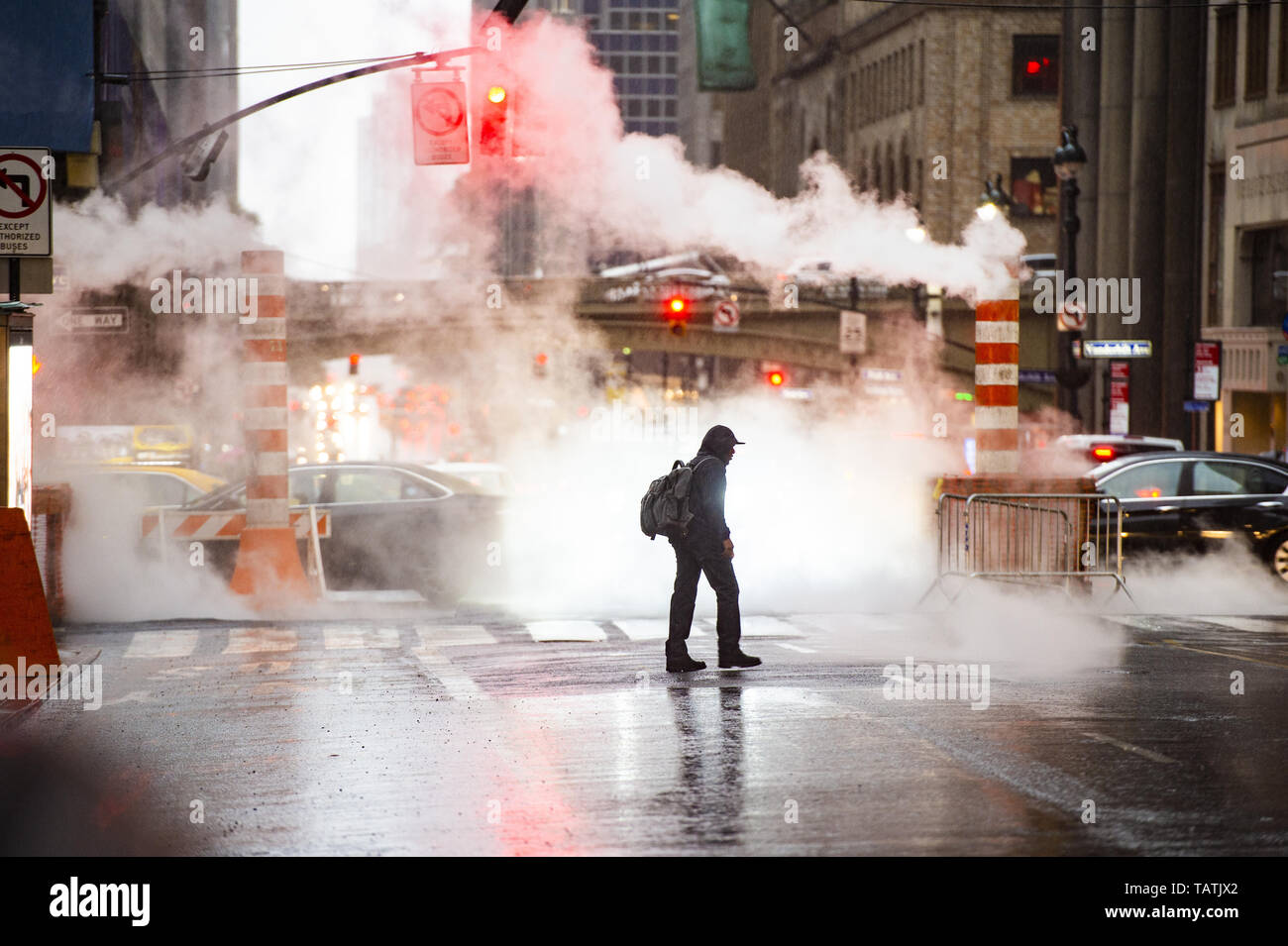 Un maschio nero sta attraversando il 42nd street a Manhattan mentre il vapore che fuoriesce dai tombini. Foto Stock