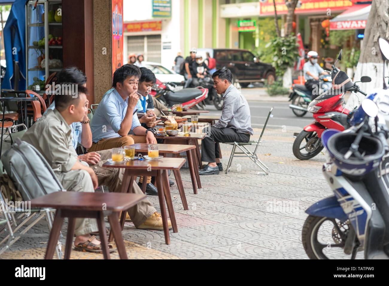Da Nang, Vietnam - Marzo 14, 2019: persone sedersi ai tavolini (con caffè, tè e altre bevande) sul marciapiede. Foto Stock
