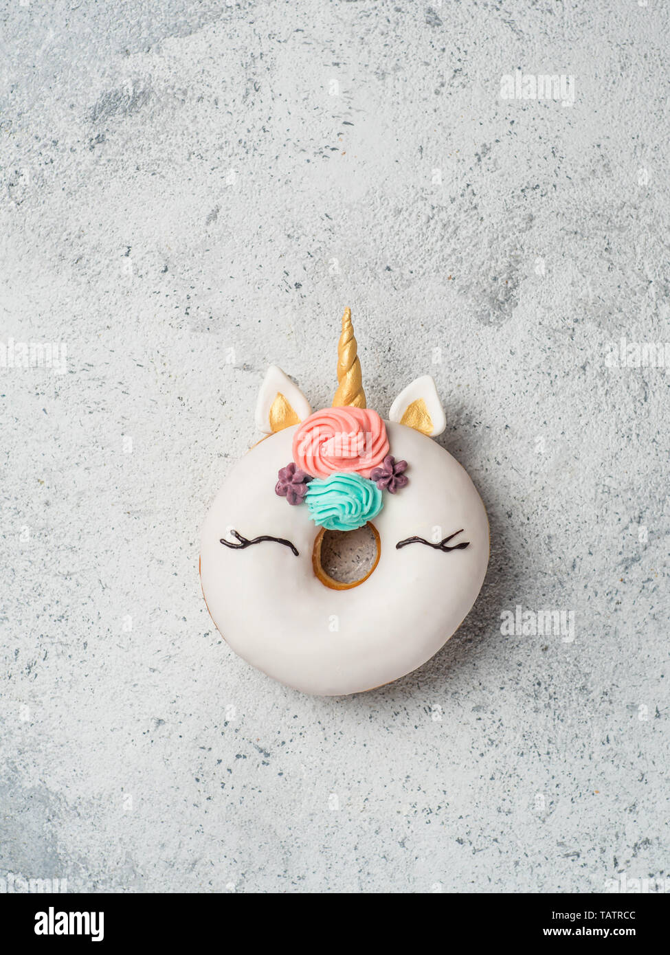 Unicorn ciambella su cemento grigio Sfondo. Ciambella alla moda unicorn con smalto bianco. Vista superiore piatta o laici. Copia spazio per il testo. Verticale. Foto Stock